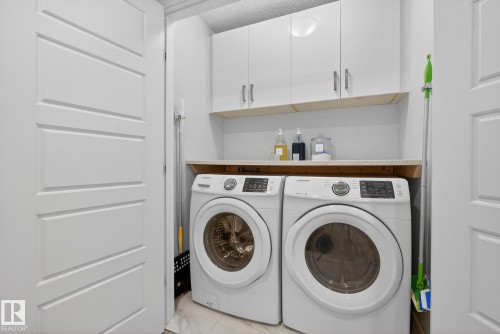 Washroom featuring cabinet space, washer and clothes dryer, and a textured ceiling - 17727 13 Avenue, Edmonton, AB - Indoor Photo Showing Laundry Room