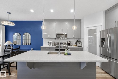 Kitchen with gray cabinets, appliances with stainless steel finishes, light stone counters, light wood-style floors, and recessed lighting - 17727 13 Avenue, Edmonton, AB - Indoor Photo Showing Kitchen With Upgraded Kitchen