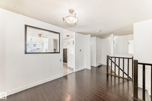 Unfurnished room featuring a textured ceiling and dark wood finished floors - 131 Saskatchewan Avenue W, Devon, AB - Indoor Photo Showing Other Room
