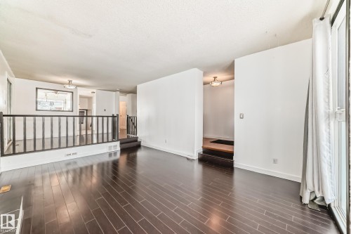 Unfurnished room featuring dark wood-style flooring and a textured ceiling - 131 Saskatchewan Avenue W, Devon, AB - Indoor Photo Showing Other Room
