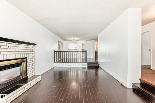 Unfurnished living room featuring a fireplace, dark wood-type flooring, and a textured ceiling - 131 Saskatchewan Avenue W, Devon, AB - Indoor With Fireplace