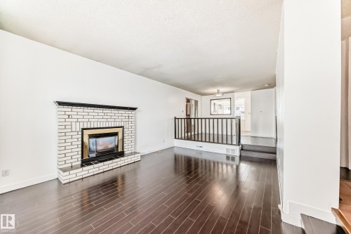 Unfurnished living room featuring a fireplace, dark wood-type flooring, and a textured ceiling - 131 Saskatchewan Avenue W, Devon, AB - Indoor Photo Showing Living Room With Fireplace