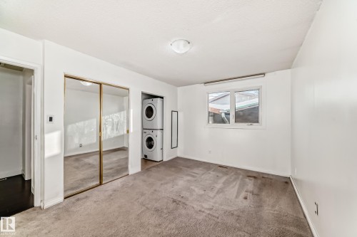 Unfurnished bedroom with carpet flooring, stacked washer / drying machine, and a textured ceiling - 131 Saskatchewan Avenue W, Devon, AB - Indoor Photo Showing Other Room