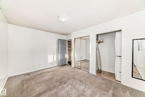 Unfurnished bedroom with carpet, estacked washer and dryer, and a closet - 131 Saskatchewan Avenue W, Devon, AB - Indoor Photo Showing Other Room