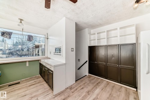 Kitchen featuring light wood-style flooring, a textured ceiling, dark brown cabinetry, tile counters, and a ceiling fan - 131 Saskatchewan Avenue W, Devon, AB - Indoor