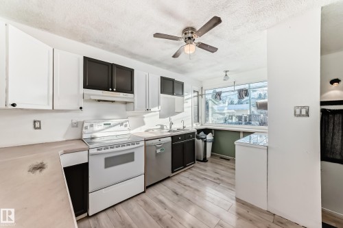 Kitchen with white range with electric stovetop, light countertops, white cabinetry, light wood finished floors, and a textured ceiling - 131 Saskatchewan Avenue W, Devon, AB - Indoor Photo Showing Kitchen