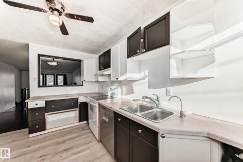 Kitchen with open shelves, light countertops, white range with electric cooktop, white cabinets, and a textured ceiling - 131 Saskatchewan Avenue W, Devon, AB - Indoor Photo Showing Kitchen With Double Sink