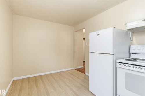Kitchen with white appliances, light wood-style floors, and under cabinet range hood - 10332 82 Street, Edmonton, AB - Indoor Photo Showing Kitchen