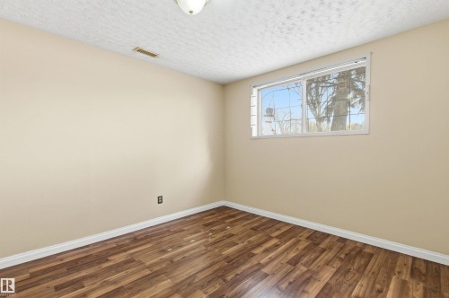 Empty room with dark wood-type flooring and a textured ceiling - 10332 82 Street, Edmonton, AB - Indoor Photo Showing Other Room