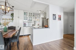 Kitchen featuring dark countertops, glass insert cabinets, open shelves, freestanding refrigerator, and tasteful backsplash - 