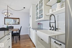 Kitchen with white cabinets, open shelves, glass insert cabinets, and dark wood-type flooring - 