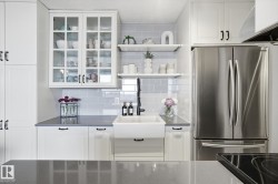 Kitchen with open shelves, white cabinetry, freestanding refrigerator, and dark stone countertops - 