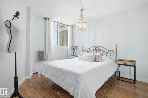 Bedroom with dark wood-style floors and a chandelier - 1513 13910 Stony Plain Road, Edmonton, AB - Indoor Photo Showing Bedroom