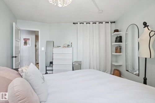 Bedroom with a chandelier and a textured ceiling - 1513 13910 Stony Plain Road, Edmonton, AB - Indoor Photo Showing Bedroom
