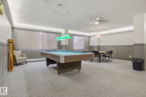 Playroom featuring a wainscoted wall, a decorative wall, pool table, a textured ceiling, and baseboard heating - 1513 13910 Stony Plain Road, Edmonton, AB - Indoor Photo Showing Other Room