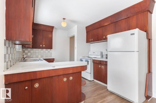 Kitchen with a peninsula, white appliances, light countertops, and dark brown cabinets - 3810 110 Avenue, Edmonton, AB - Indoor Photo Showing Kitchen With Double Sink