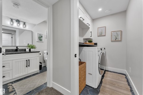 Laundry area featuring light tile patterned flooring, separate washer and dryer, and cabinet space - 7613 16 Ave Sw, Edmonton, AB - Indoor Photo Showing Laundry Room
