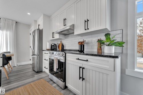 Kitchen featuring plenty of natural light, stainless steel appliances, white cabinets, dark stone counters, and recessed lighting - 7613 16 Ave Sw, Edmonton, AB - Indoor Photo Showing Kitchen