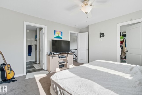Bedroom with light colored carpet, ceiling fan, a spacious closet, and ensuite bath - 2039 Wonnacott Way, Edmonton, AB - Indoor Photo Showing Bedroom