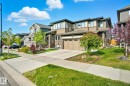 View of front facade featuring driveway, an attached garage, stone siding, and a front lawn - 2039 Wonnacott Way, Edmonton, AB  - Outdoor With Facade 