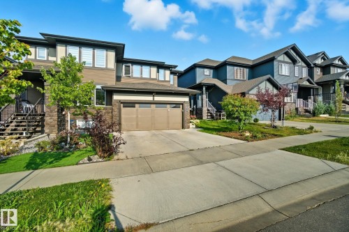 View of front of home with stairs, driveway, stone siding, and an attached garage - 2039 Wonnacott Way, Edmonton, AB - Outdoor With Facade