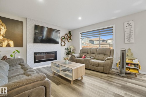 Living area featuring wood finished floors, a large fireplace, and recessed lighting - 2039 Wonnacott Way, Edmonton, AB - Indoor Photo Showing Living Room With Fireplace