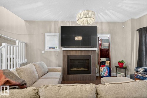 Living area with a glass covered fireplace and wood finished floors - 9858 72 Avenue, Edmonton, AB - Indoor Photo Showing Living Room With Fireplace