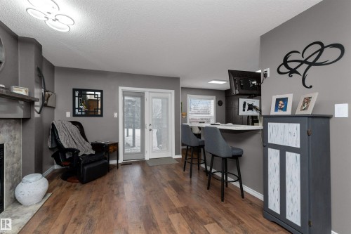 Family room off the kitchen with a breakfast bar, laminate flooring, open shelves, and a fireplace - 5628 188A Street, Edmonton, AB - Indoor
