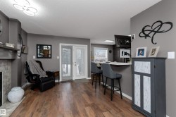 Family room off the kitchen with a breakfast bar, laminate flooring, open shelves, and a fireplace - 