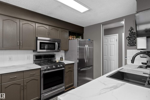 Kitchen with backsplash, stainless steel appliances, and light stone countertops - 5628 188A Street, Edmonton, AB - Indoor Photo Showing Kitchen With Stainless Steel Kitchen