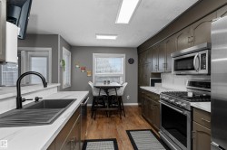 Kitchen featuring stainless steel appliances, laminate flooring, light stone countertops - 