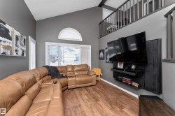 Living room with laminate flooring, custom venetian blinds, and high vaulted ceiling - 