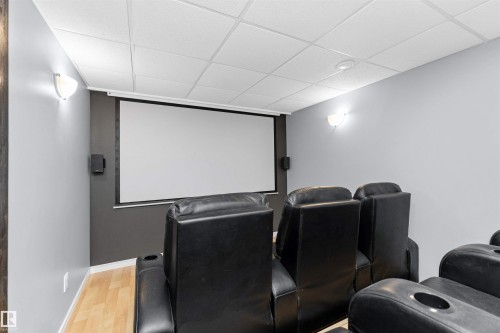 Theatre room featuring tiered seating, projector, motorized screen, and built-in shelving - 5628 188A Street, Edmonton, AB - Indoor Photo Showing Other Room