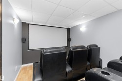 Theatre room featuring tiered seating, projector, motorized screen, and built-in shelving - 