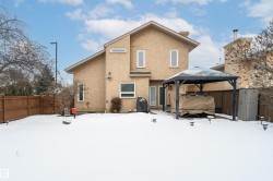 Snow covered house with a fenced backyard, stucco siding, a gate, and a steel gazebo - 