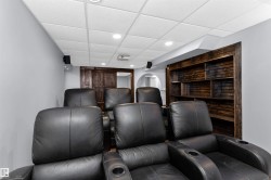 Theatre room featuring tiered seating, projector, motorized screen, and built-in shelving - 