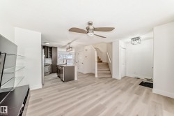 Unfurnished living room featuring stairs, light wood-type flooring, ceiling fan, and a chandelier - 