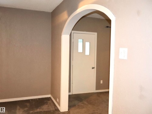 Entryway with arched walkways and dark carpet - 4511 53 Ave, Barrhead, AB - Indoor Photo Showing Other Room