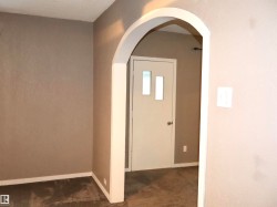 Entryway with arched walkways and dark carpet - 