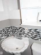 Half bathroom featuring a sink and decorative backsplash - 