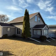Rear view of house featuring stucco siding and a shingled roof - 