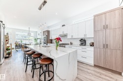 Kitchen featuring white cabinetry, hanging light fixtures, a barn door, a breakfast bar, and decorative backsplash - 