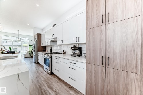 Kitchen with white cabinetry, appliances with stainless steel finishes, light stone counters, light wood-style floors, and recessed lighting - 8321 80 Avenue, Edmonton, AB - Indoor Photo Showing Kitchen