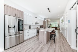 Kitchen featuring stainless steel appliances, white cabinets, tasteful backsplash, pendant lighting, and a breakfast bar area - 