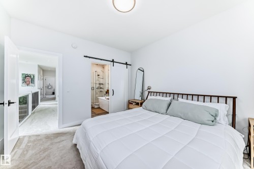Bedroom with a barn door, light colored carpet, and ensuite bathroom - 8321 80 Avenue, Edmonton, AB - Indoor Photo Showing Bedroom