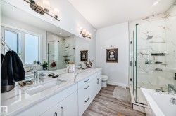 Bathroom featuring a marble finish shower, double vanity, light wood-style flooring, and a bathtub - 