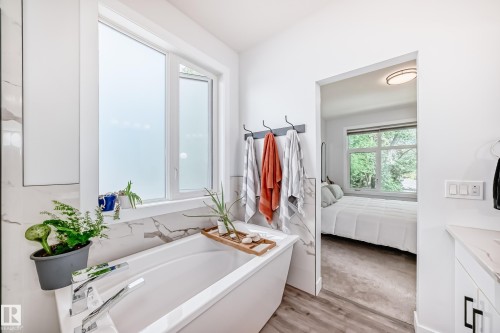 Bathroom featuring connected bathroom, vanity, a soaking tub, and light wood-type flooring - 8321 80 Avenue, Edmonton, AB - Indoor Photo Showing Bathroom