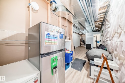 Unfinished basement with light wood-style floors and freestanding refrigerator - 8321 80 Avenue, Edmonton, AB - Indoor