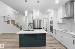 Kitchen with wall chimney exhaust hood, a center island with sink, light wood-style floors, pendant lighting, and recessed lighting - 