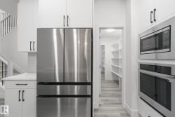 Kitchen with stainless steel appliances, white cabinetry, and light wood finished floors - 